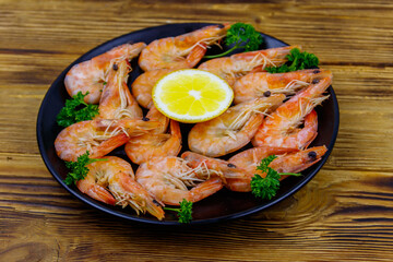 Red boiled prawns with lemon and parsley on wooden table