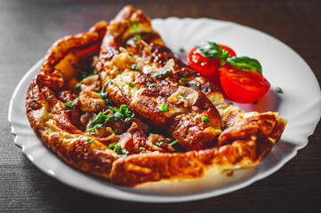 omelette with bacon in a white plate on wooden table