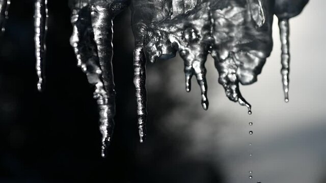 slowmotion of dripping icicles on a warm bright sunny day. Melting icicle on a blue background, seamless loop. Endless loop, loopable