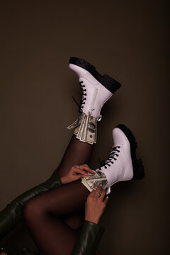 Close up view of dollar bills in shoes on dark background.Boots full of money on a dark background. Image isolated on dark green studio background.
