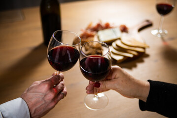 Making a toast by clinking two glasses with red wine.