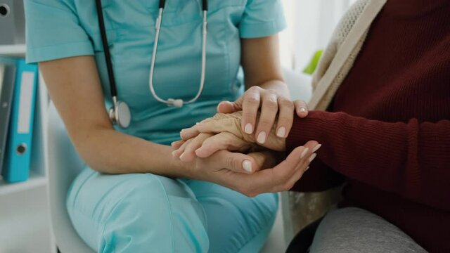doctor holding hands of old woman during medical appointment