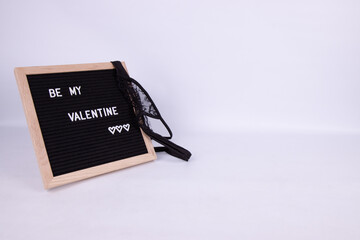 A sign that says Be My Valentines draped with black lingerie panties or knickers on a white...