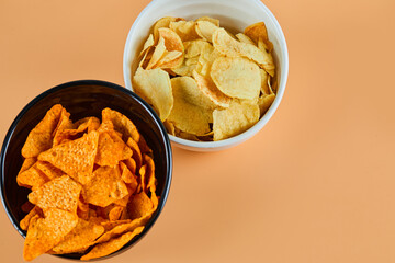 Two bowls of chips on orange background