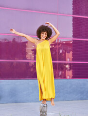Obraz premium Woman with afro hair. She has a yellow dress and behind is a purple background