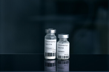 Coronavirus vaccine two small ampoules with two-component vaccine stand on a dark mirror table