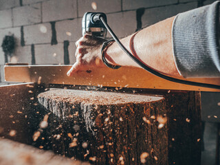 close-up of a carpenter working with an electric fraser. wood shavings. wood stump processing