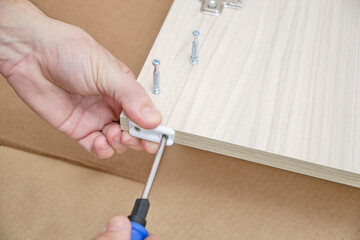 Master attaches hardware to furniture parts.Assembly of cabinet furniture.
