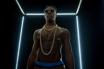Serious rapper in gold chains, bottom view - obrazy, fototapety, plakaty