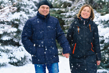 couple walking in a winter forest, two adult people, man and woman, beautiful nature with bright snowy fir trees