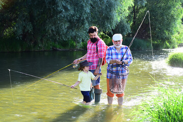 Great-grandfather and great-grandson. Fishing became a popular recreational activity. Happy grandfather, father and grandson with fishing rods on river berth.