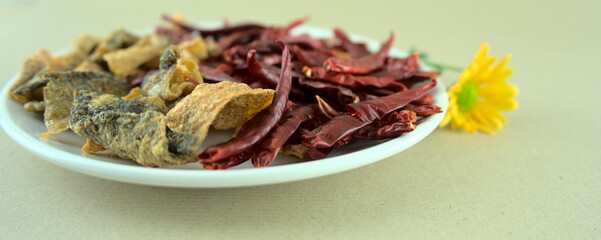 Crispy salted fish skins with dried red hot chilis. Fired, baked snack or starter. Spicy asian food style photography, ocean products, merchant, fish manufacturing concept.