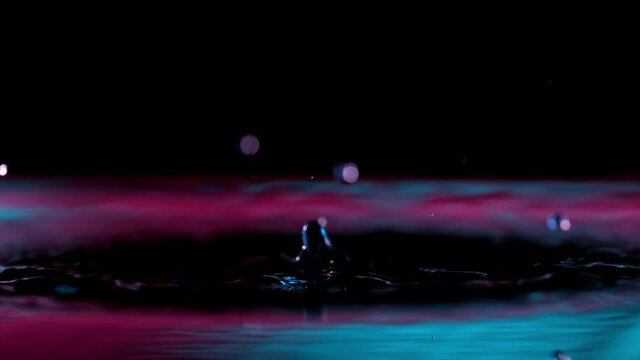 Super slow motion of splashing water crown illuminated by neon lights. Filmed on very high speed camera, 1000 fps.