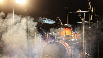 Fotografía de un set de batería en un escenario con humo y luces. Espectáculos.