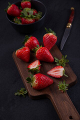Fresh strawberries on black background, laid out on top of a wood.
