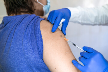 close up doctor holding syringe and using cotton before make injection to patient in medical mask. Covid-19 or coronavirus vaccine