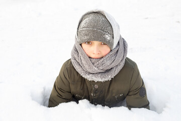10 yeras boy in winter snow has fun in warm cloth. Cold weather concept close up photo