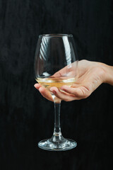 Holding a glass of white wine on black background