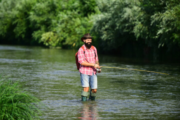 Man fishing and relaxing while enjoying hobby. A fisherman with fishing rod on the river. Fisherman and trout. Holding brown trout.