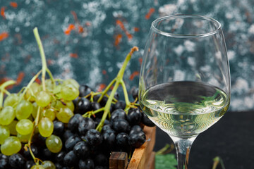 White wine in a glass with a bunch of green grapes around