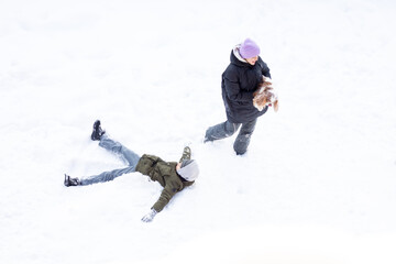 Fototapeta na wymiar girl and boy are having fun outdoors, day is snowing, sister and brother laughing sparklers dog play snow in winter warm clothes