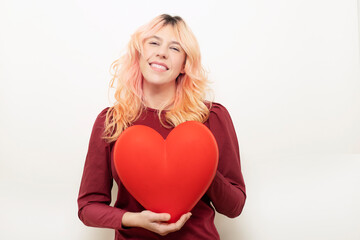 beautiful woman smiling at the camera while holding a big valentine's day heart