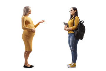 Full length profile shot of a pregnant woman in a yellow dress talking to a student with books