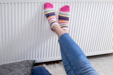 woman warming her foots in sock with radiator 