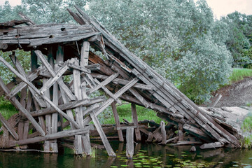 Logs of pillars of an old wooden bridge. Destroyed wooden old bridge. Building structure of a destroyed wooden bridge.