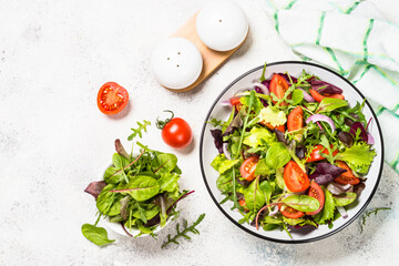 Green salad from fresh salad leaves and vegetables in white plate. Healthy vegan food. Top view image.