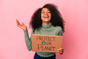 Young african american curly woman receiving a pleasant surprise, excited and raising hands.