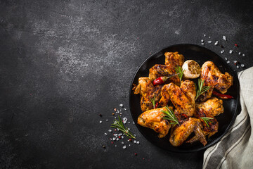 Grilled chicken wings with spices at black table. Top view with space for design. © nadianb