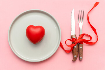 Valentine's Day romantic dinner, dating, love concept. tabble serving with cutlery and heart decor on pink background. Top view flatlay