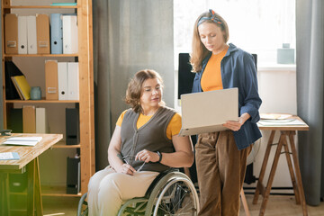 Young confident businesswoman showing online data to her disable colleague