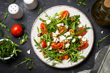 Arugula salad with tomatoes, blue cheese and walnuts. Healthy vegetarian dish. Top view image.