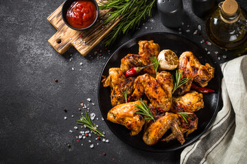 Grilled chicken wings with spices at black table. Top view with space for design.
