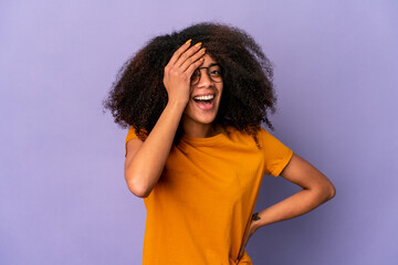 Fototapeta na wymiar Young african american curly woman isolated on purple background having fun covering half of face with palm.