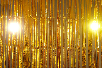 Metallic tinsel background. Bright gold foil fringe curtains hung as interior decor or photo...
