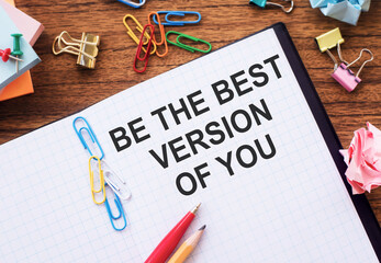 Notepad with the text BE THE BEST VERSION OF YOU on the table, with colored paper clips and crumpled sheets.