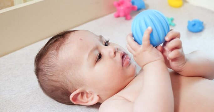 infant, childhood concept - close-up of smiling happy Baby plays with a teether. Teeth cutting. First teeth. Joy toothless 7 months baby bite, gnaws teether toy