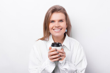 Portrait of cheerful young beautiful woman holding white cup of coffee to take away.