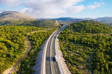 Aerial view on road. Highway throu mountain valley. View from a drone. Natural landscape in summer time from air. Travel and vacation. Transportation image