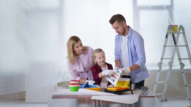 family relationships, young parents and female child enjoy renovation and choose wall paint from color palette while decorating apartment