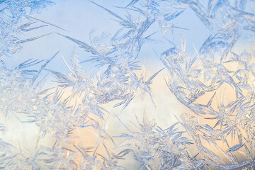 Frost on glass window. Abstract macro wallpaper bright background. Blue and pink crystal ice texture in sunlight