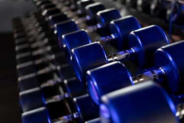 Fototapeta na wymiar Dumbbells in a row at gym Dark toned