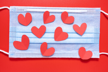 Medical mask with a heart on a red background. Valentine's Day.