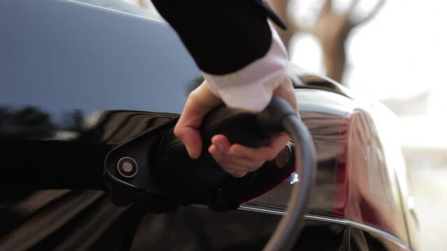 coche el&eacute;ctrico se recarga en toma de corriente mano negro