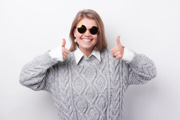 Cheerful young woman in causal wearing sunglasses and showing thumb up.