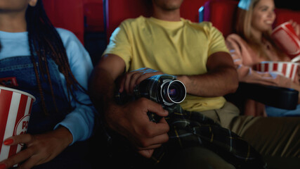 Cropped shot of a guy recording a pirated movie at the cinema