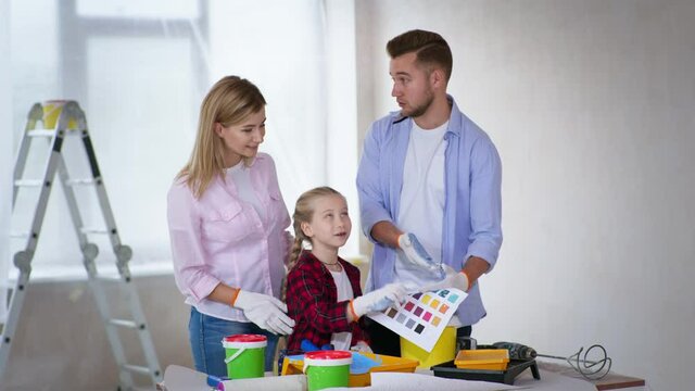 portrait of friendly family of parents and daughter enjoy making repairs and choosing paint for walls during finishing work in apartment